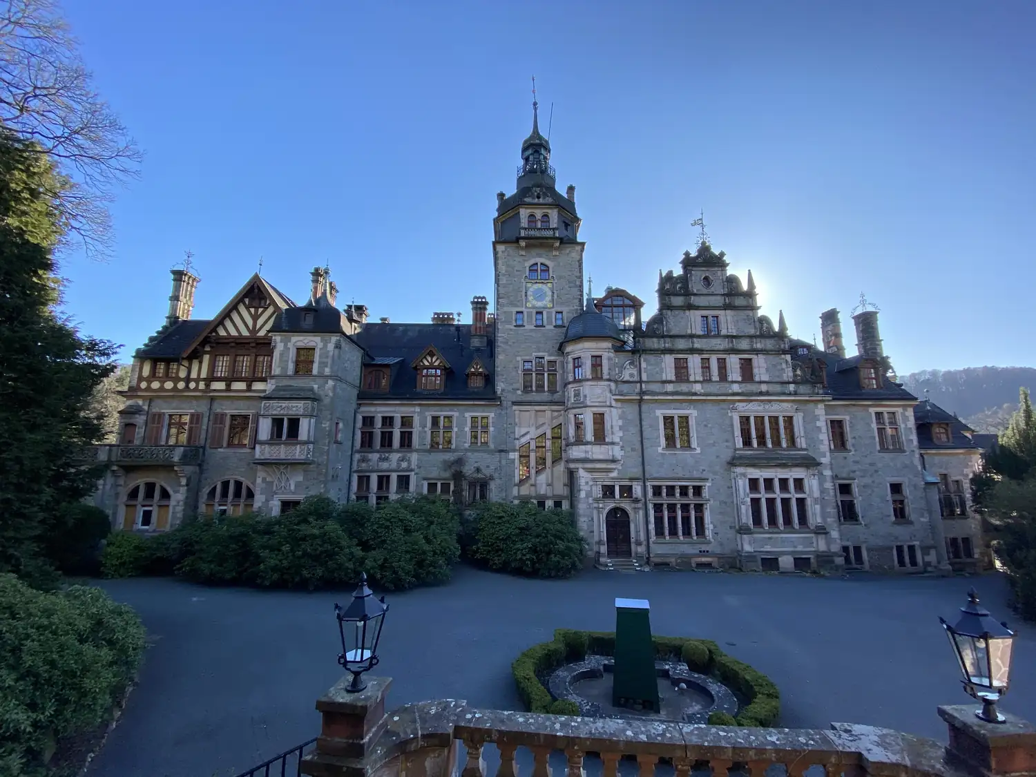 Schloss Ramholz von der Vorfahrt aus: Hauptfassade mit Uhrturm, barockem Volutengiebel und Tudor-Fachwerkgiebel